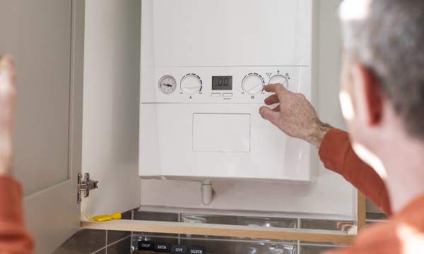 Aufnahme eines Mannes, der eine Kombitherme einer Gasheizung abliest