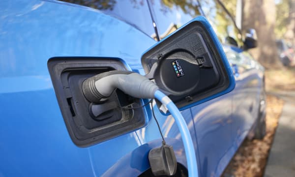 Nahaufnahme eines blauen E-Autos, das gerade geladen wird