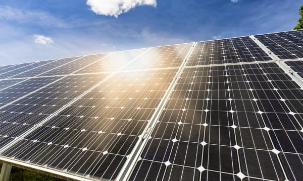 Nahaufnahme von schwarzen Photovoltaik-Modulen auf einem Dach, auf die die Sonne scheint