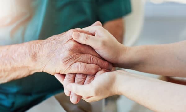 Eine jüngere und eine ältere Person halten sich die Hände, Nahaufnahme der Hände