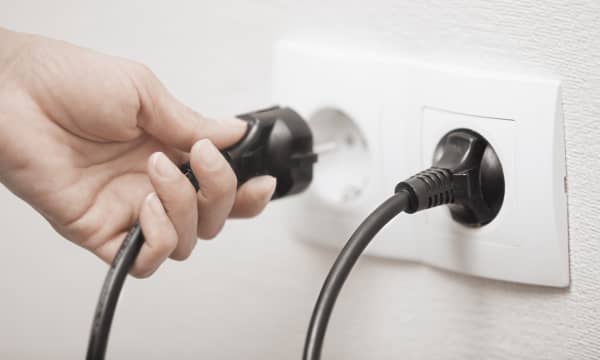 Frau steckt einen Stecker in eine Steckdose, Nahaufnahme ihrer Hand