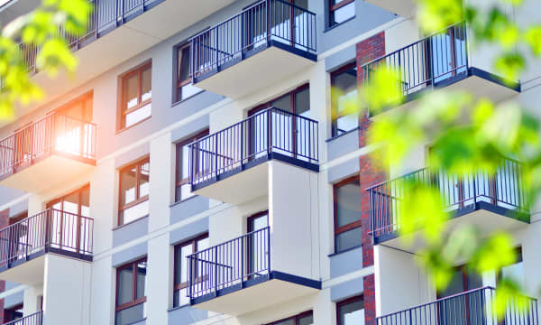 Fassade eines Mehrfamilienhaus-Neubaus mit heller Fassade und Balkons