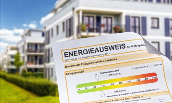 Energieausweis mit modernem Mehrfamilienhaus im Hintergrund