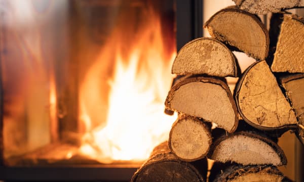 Aufgestapelte Holzscheite vor einem brennenden Kamin