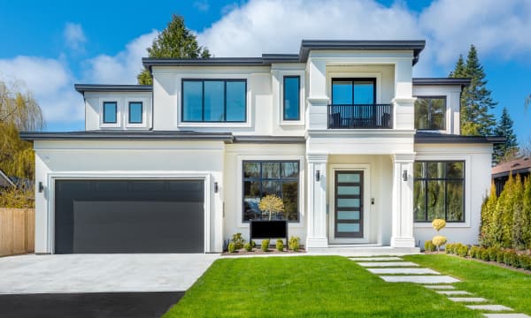 Frontansicht eines modernen Einfamilienhauses mit Garage, davor gepflegter Rasen