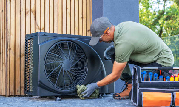 Monteur arbeitet im Freien an einer schwarzen Wärmepumpe