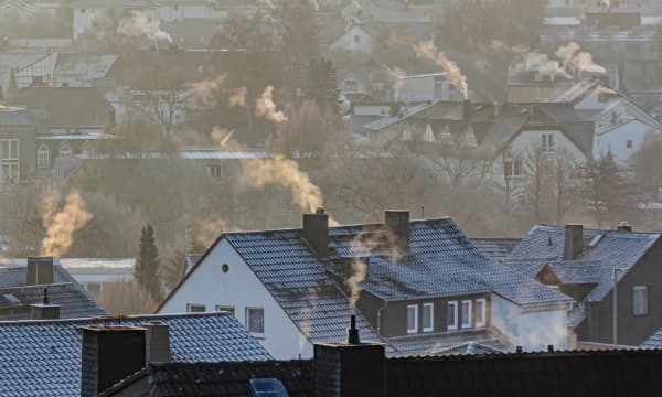 Wohnhäuser mit qualmenden Schornsteinen im Winter