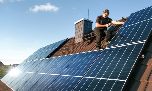 Handwerker installiert Solarmodule auf dem Dach eines Einfamilienhauses