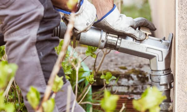 Mann in Arbeitskleidung nutzt einen Anschluss zum Betanken mit Heizöl an einem Haus