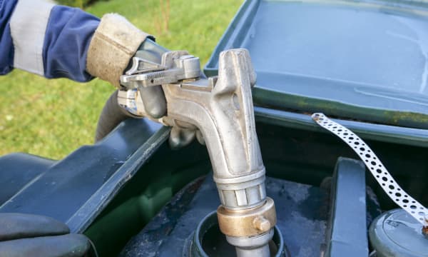 Heizöltank wird von einer Person mit Arbeitshandschuhen betankt