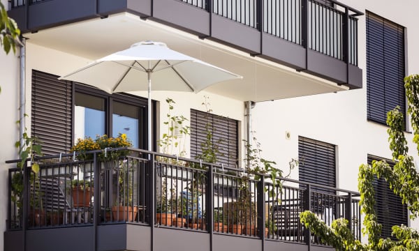 Balkon mit Pflanzen und Sonnenschirm an einem modernen Mehrfamilienhaus