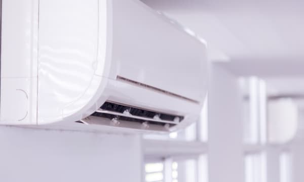 Nahansicht des Innengeräts einer fest installierten Klimaanlage in einem Raum mit weißen Wänden