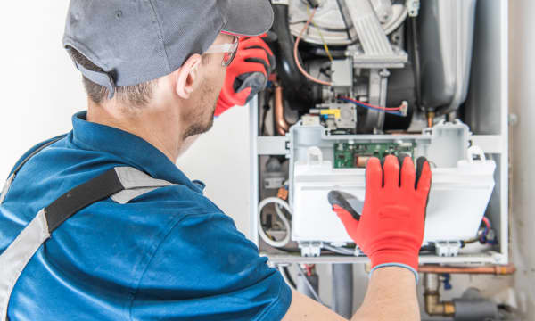 Handwerker in Arbeitskleidung arbeitet an einer Gastherme