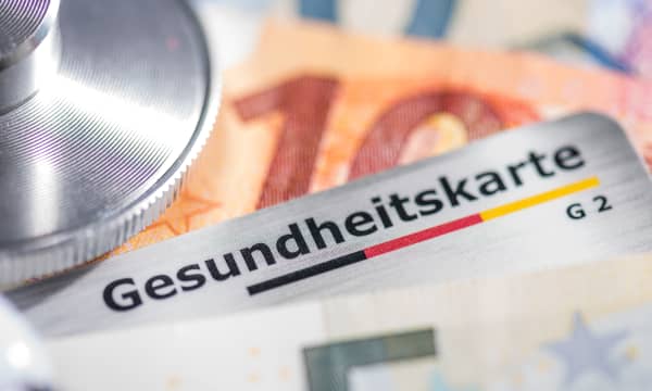 Nahaufnahme von Stethoskop, Gesundheitskarte und mehreren Euroscheinen