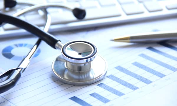 Stethoskop, Kugelschreiber, Finanzübersicht und Computertastatur auf einem Tisch