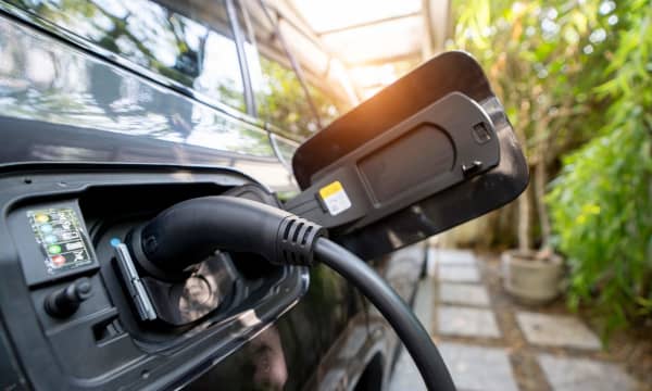 Nahaufnahme eines Elektroautos, das auf dem eigenen Grundstück an einer privaten Ladestation geladen wird