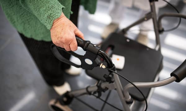 Seniorin in schwarzer Hose und grünem Oberteil mit einem Rollator