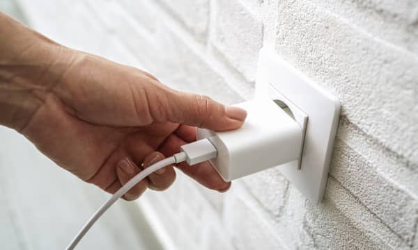 Nahaufnahme der Hand einer Person, die einen Stecker in eine Steckdose steckt