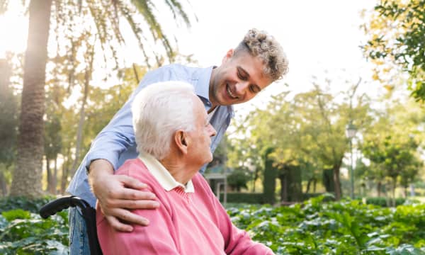 Junger Mann und Senior im Rollstuhl im Grünen
