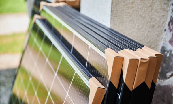 Mehrere verpackte Solarmodule lehnen am Äußeren eines Gebäudes