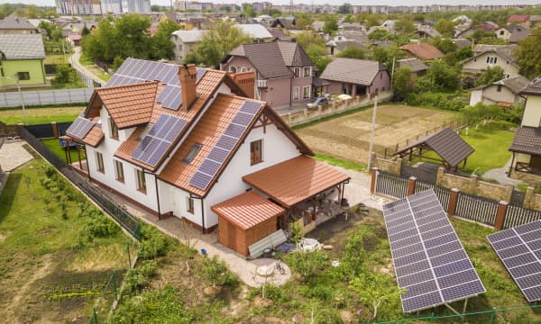 Wohnhäuser im Grünen mit Dach-Solaranlagen und freistehenden Solarmodulen