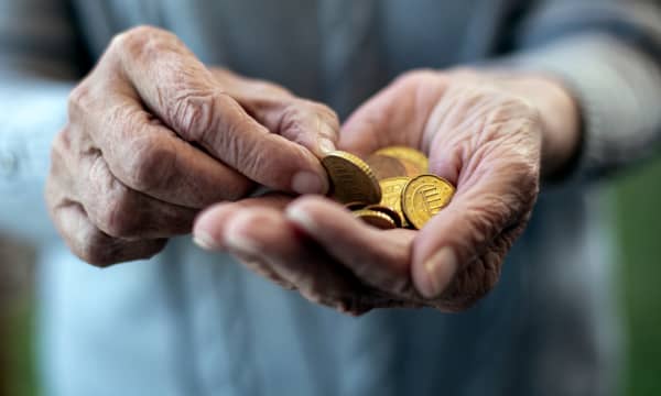 Nahaufnahme der Hände einer älteren Person. Sie hält Euromünzen in der Hand.