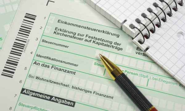 Formulare zur Einkommensteuererklärung mit Notizblock und Kugelschreiber