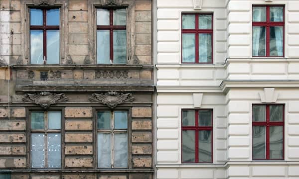 Frontansicht zweier Mehrfamilienhäuser, von denen das linke stark sanierungsbedürftig und das rechte bereits saniert ist