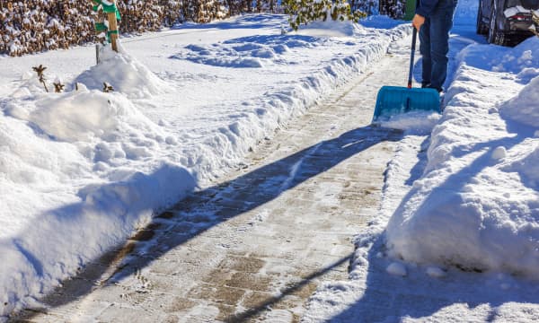 Verschneite Einfahrt, die von einer Person geräumt wird