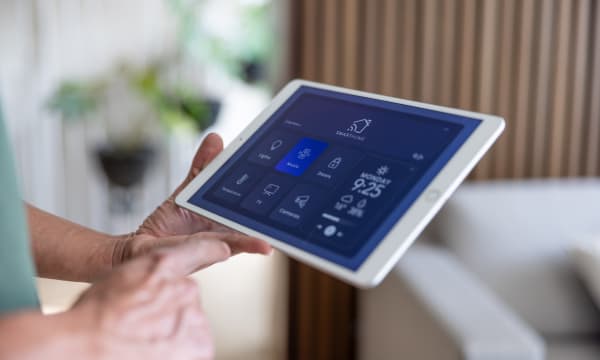Ältere Person hält ein Tablet mit Smart-Home-Anwendung