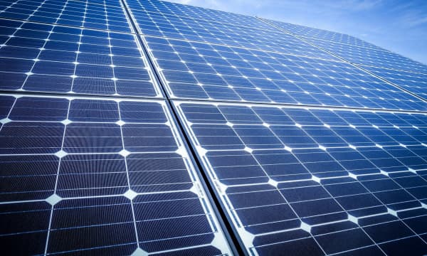 Nahaufnahme mehrerer Photovoltaikmodule auf einem Schrägdach bei blauem Himmel mit einigen Wolken