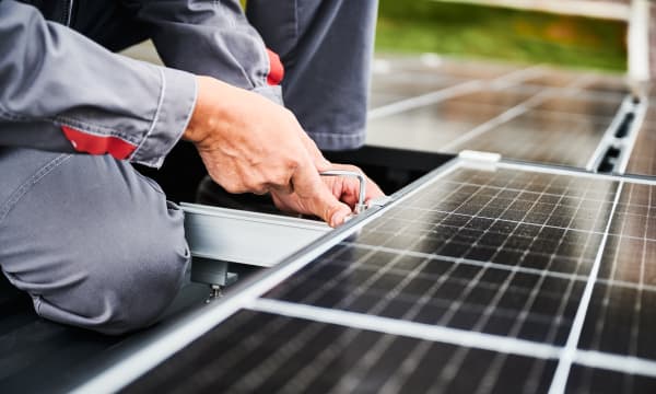 Nahaufnahme eines Arbeiters, der ein Solarmodul auf einem Dach installiert