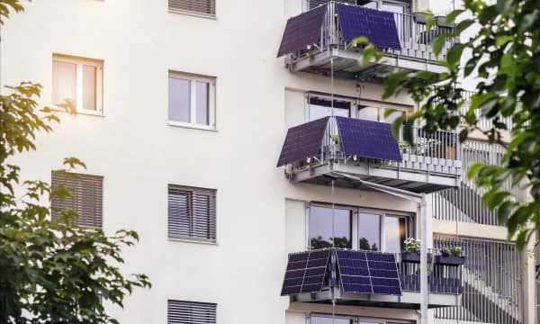 Ansicht der Fassade eines gepflegten Mehrfamilienhauses mit Balkonen, an denen sich Balkon-Solaranlagen befinden