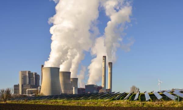 Kohlekraftwerk, Solar und Windräder vor blauem Himmel