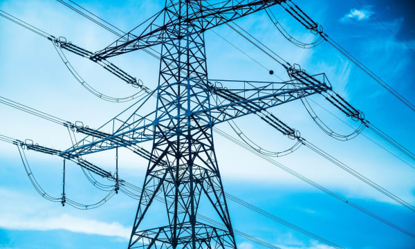 Einzelner Hochspannungsmast vor blauem Himmel