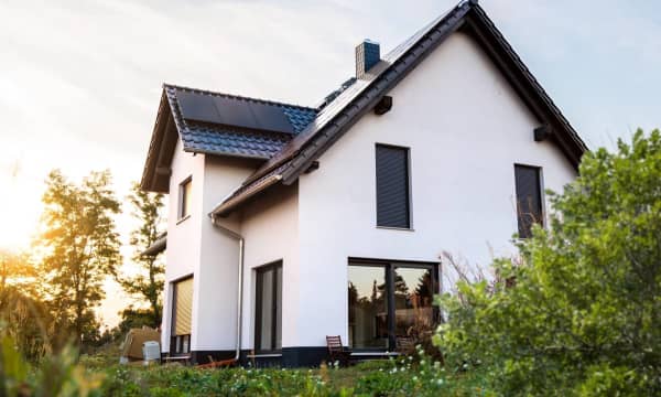 Außenansicht eines neu gebauten Einfamilienhauses in Deutschland. Das Haus ist mit Solarpanelen auf dem Dach ausgestattet und nach modernen Standards der Nachhaltigkeit gebaut.
