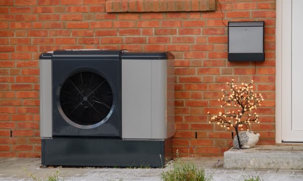 Wärmepumpe neben Eingang eines Altbaus aus rotem Backstein