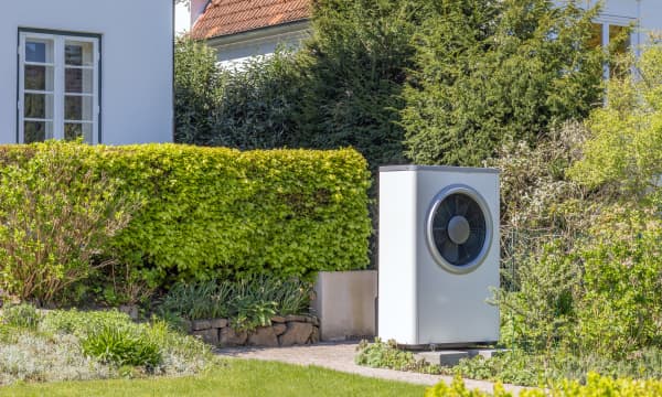 Wärmepumpe im Garten vor einem Haus im Grünen