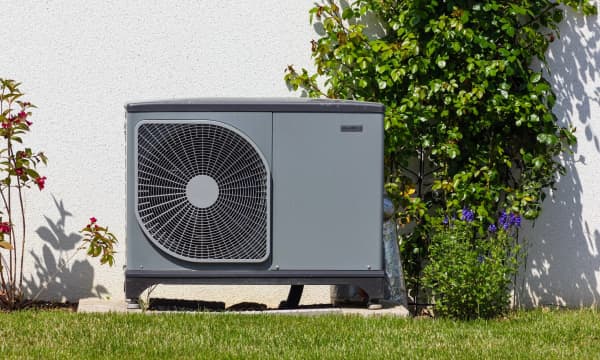 Wärmepumpe im Garten vor einem Eigenheim