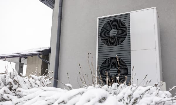 Luft-Wärmepumpen an Fassade eines Wohngebäudes im Schnee