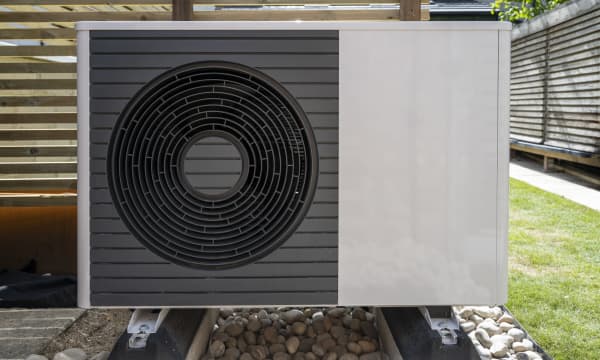 Luft-Wärmepumpe im Garten vor Holzwand zum Lärmschutz