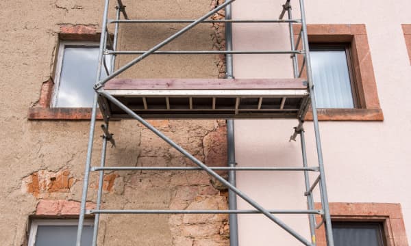 Bestandsimmobilie mit Gerüst; eine Hälfte ist saniert, eine Hälfte unsaniert