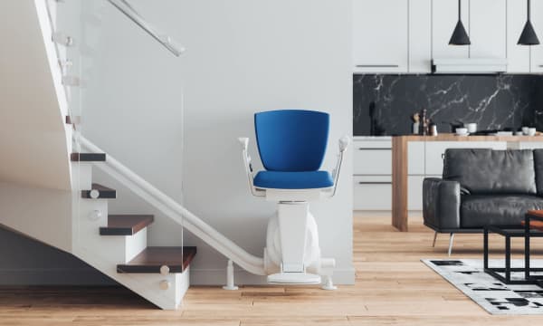 Sitzlift mit blauem Polster am Fußt einer Treppe in einem modernen Eigenheim