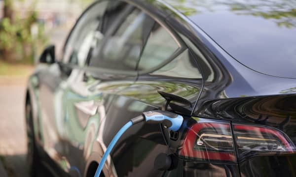 Ansicht eines schwarzen Elektroautos von hinten links mit angeschlossenem Ladekabel