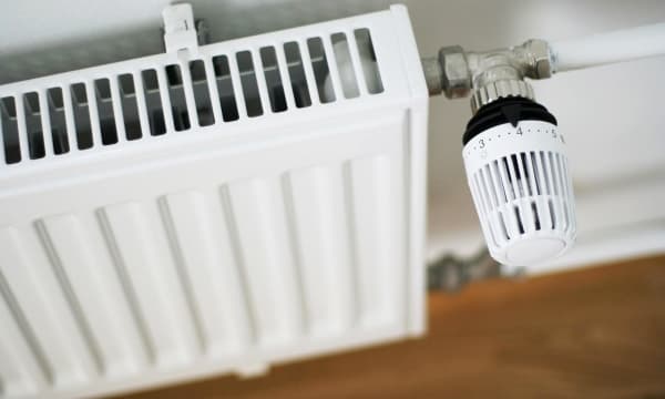 Schrägansicht von oben auf einen weißen Heizkörper. Das Thermostat ist auf Stufe 4.