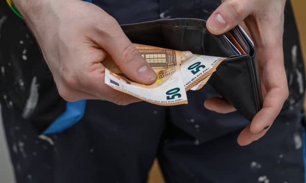 Ein Handwerker hält Geld und ein Portemonnaie in den Händen.