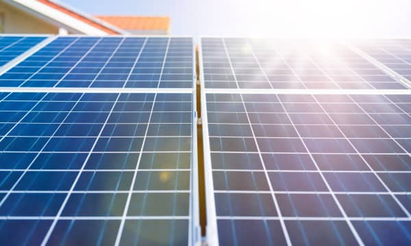 Nahaufnahme von blauen Solarmodulen mit einem klaren Rastermuster, beleuchtet von hellem Sonnenlicht. Die Module gehören zu einer Solaranlage auf einem Wohnhaus und erzeugen erneuerbare Energie zur nachhaltigen Stromversorgung.