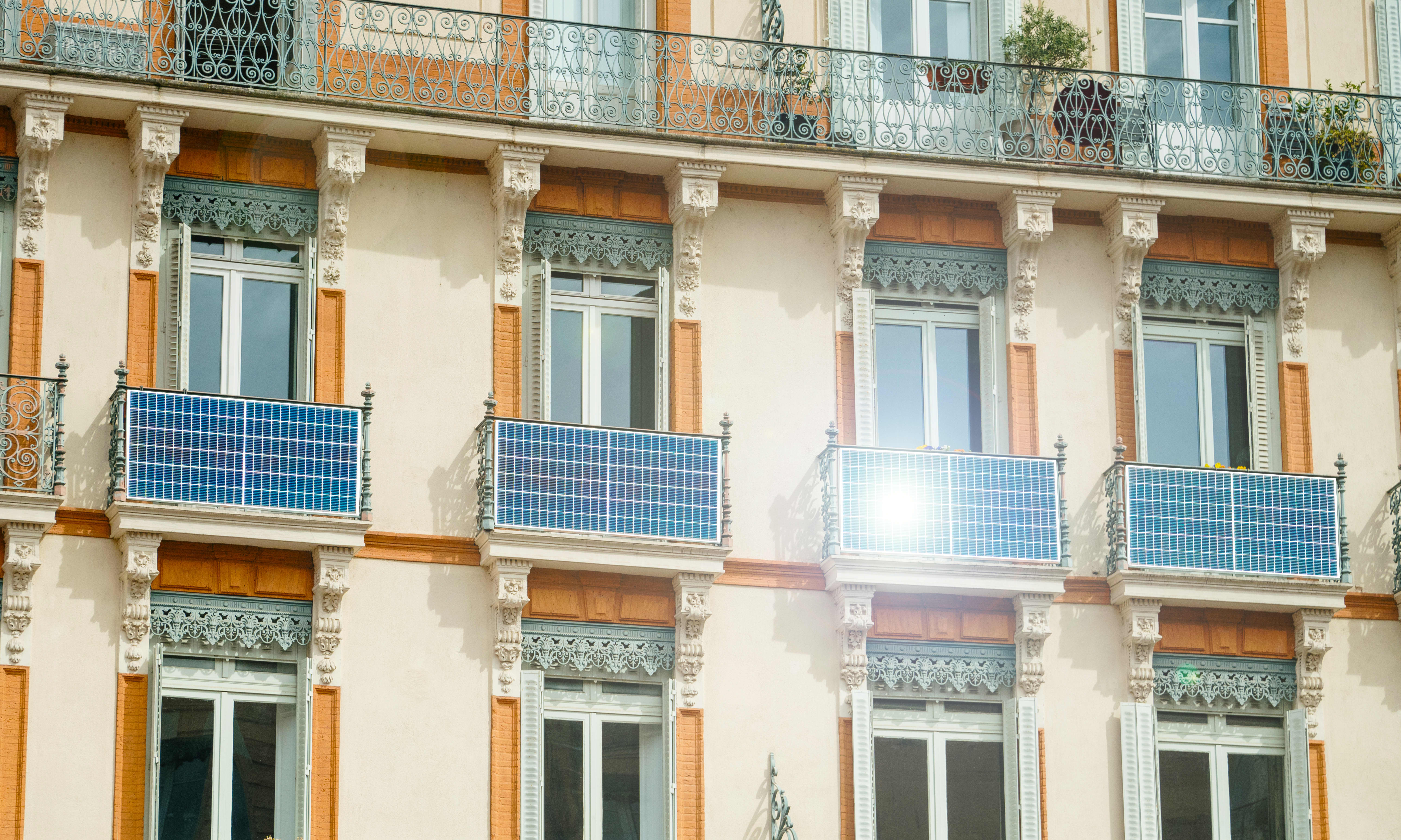 Fassade eines sanierten Altbaus mit Solarmodulen an mehreren Balkonen