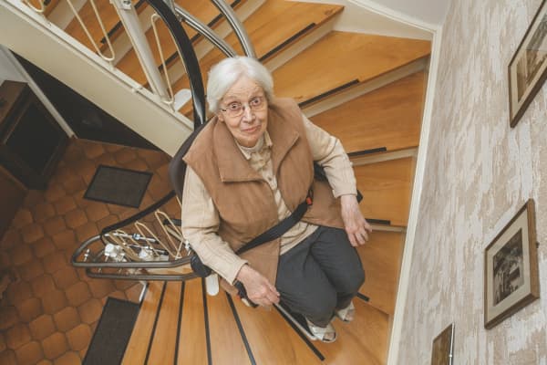 Frau im Treppenlift fährt die Treppe hoch