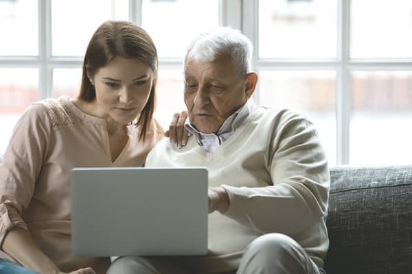 Angehörige hilft älterem Mann am PC bei Zuschüssen für Elektromobilen